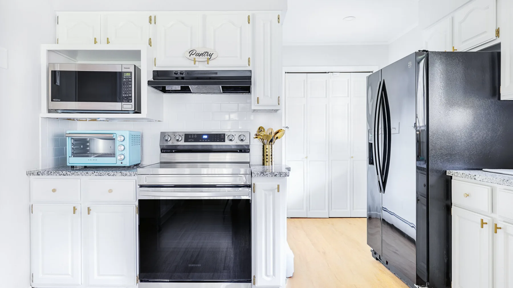 A bright kitchen with white cabinets, stainless steel appliances, and a light wood floor.