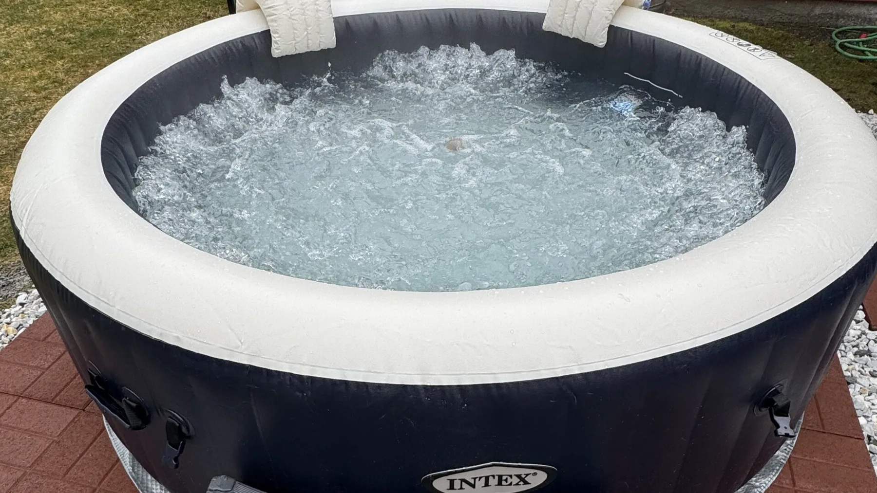 An inflatable hot tub filled with bubbling water sits outdoors.