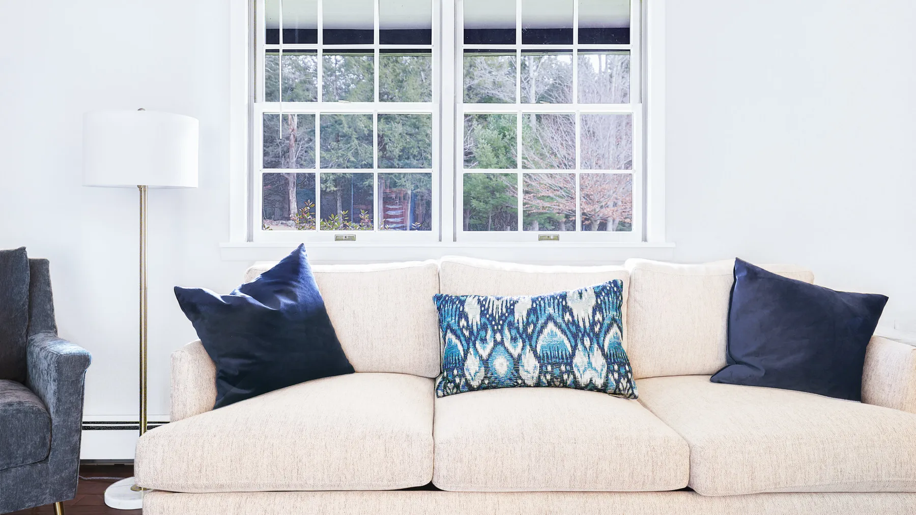 A bright living room with a cream sofa and patterned cushions.