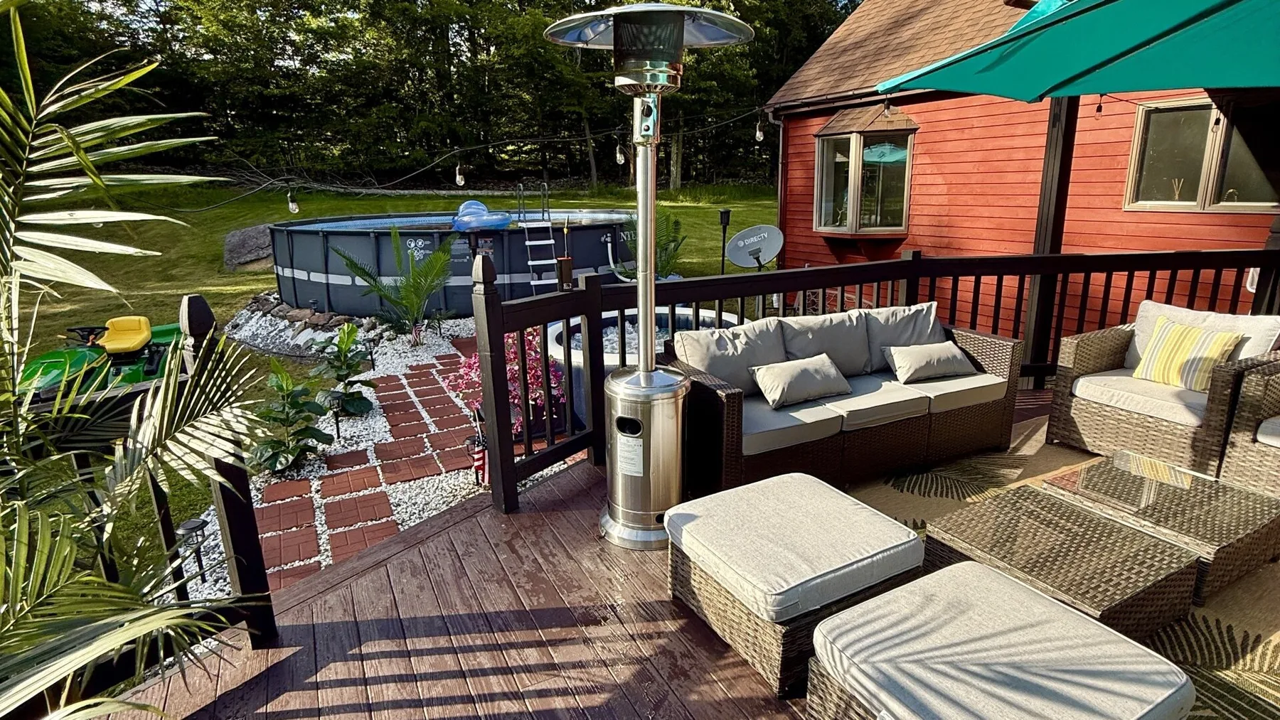 An outdoor deck with cushioned seating overlooks a swimming pool.