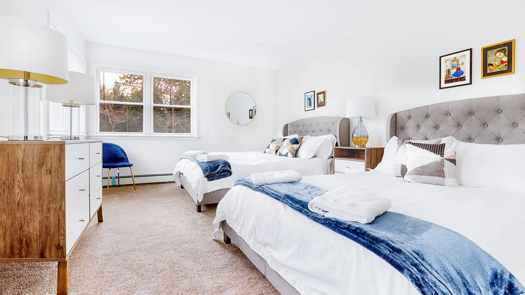 A bright bedroom with two beds, white linens, and a window.