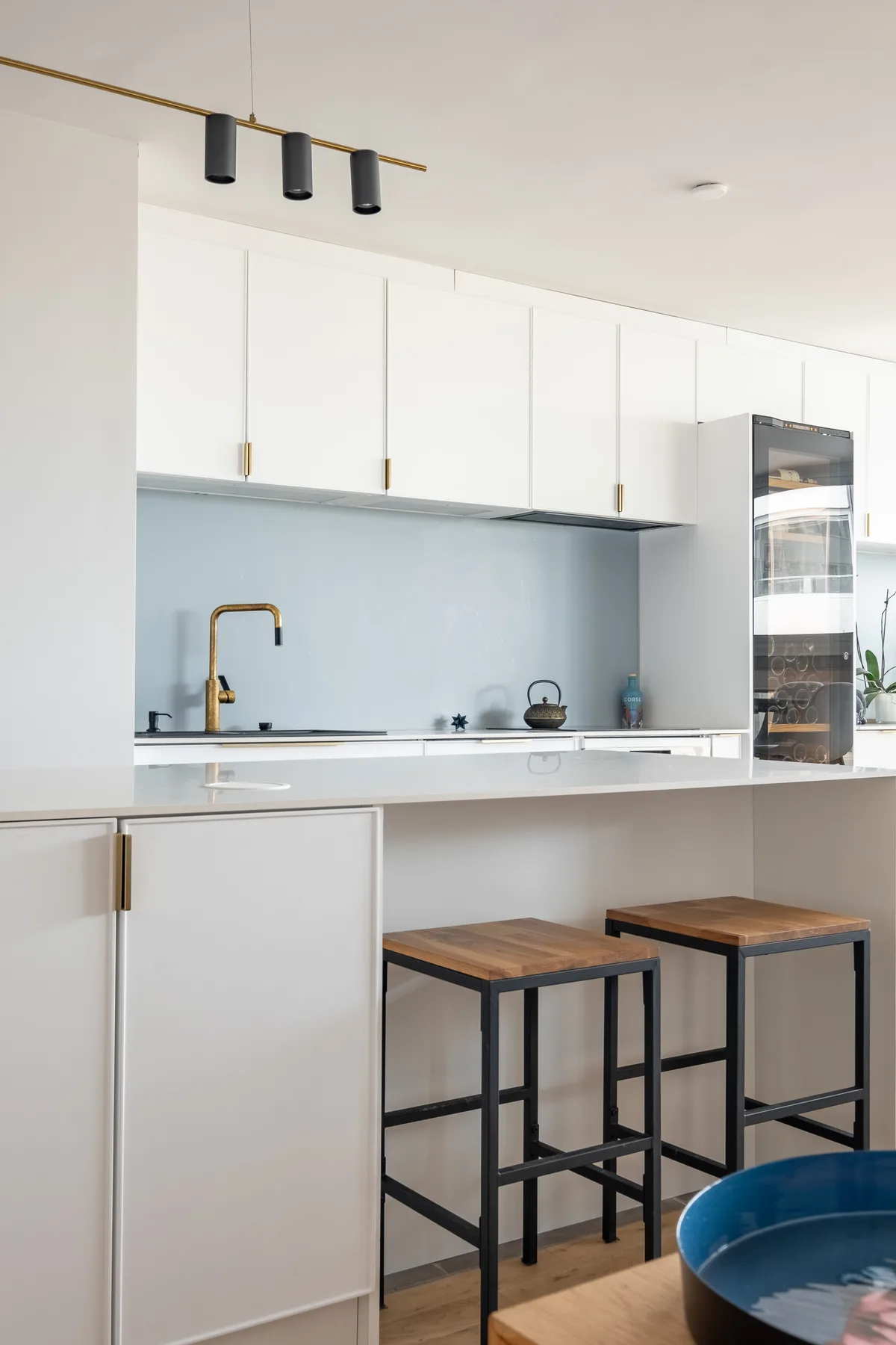 Una cocina moderna con gabinetes blancos, una encimera y taburetes.
