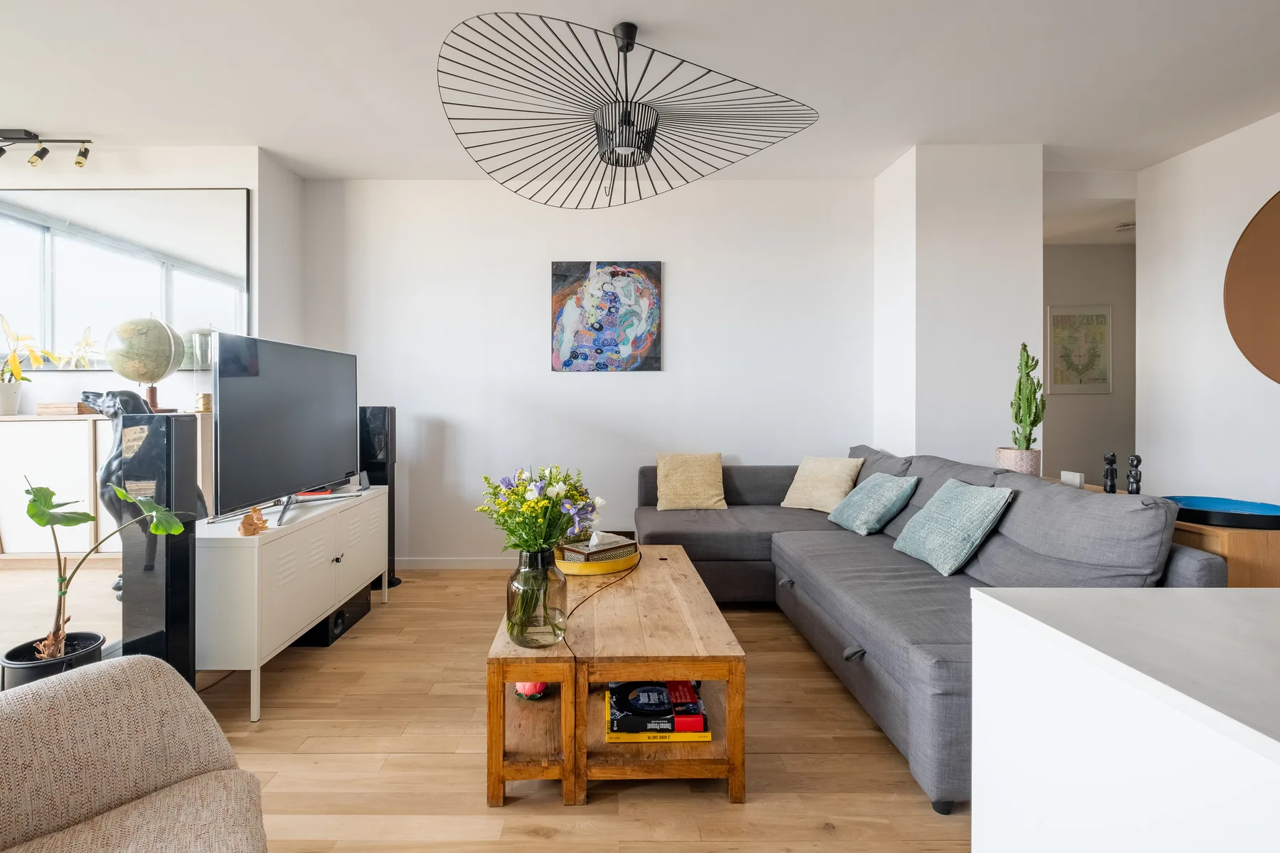 A bright living room with a gray sectional sofa and a wooden coffee table.