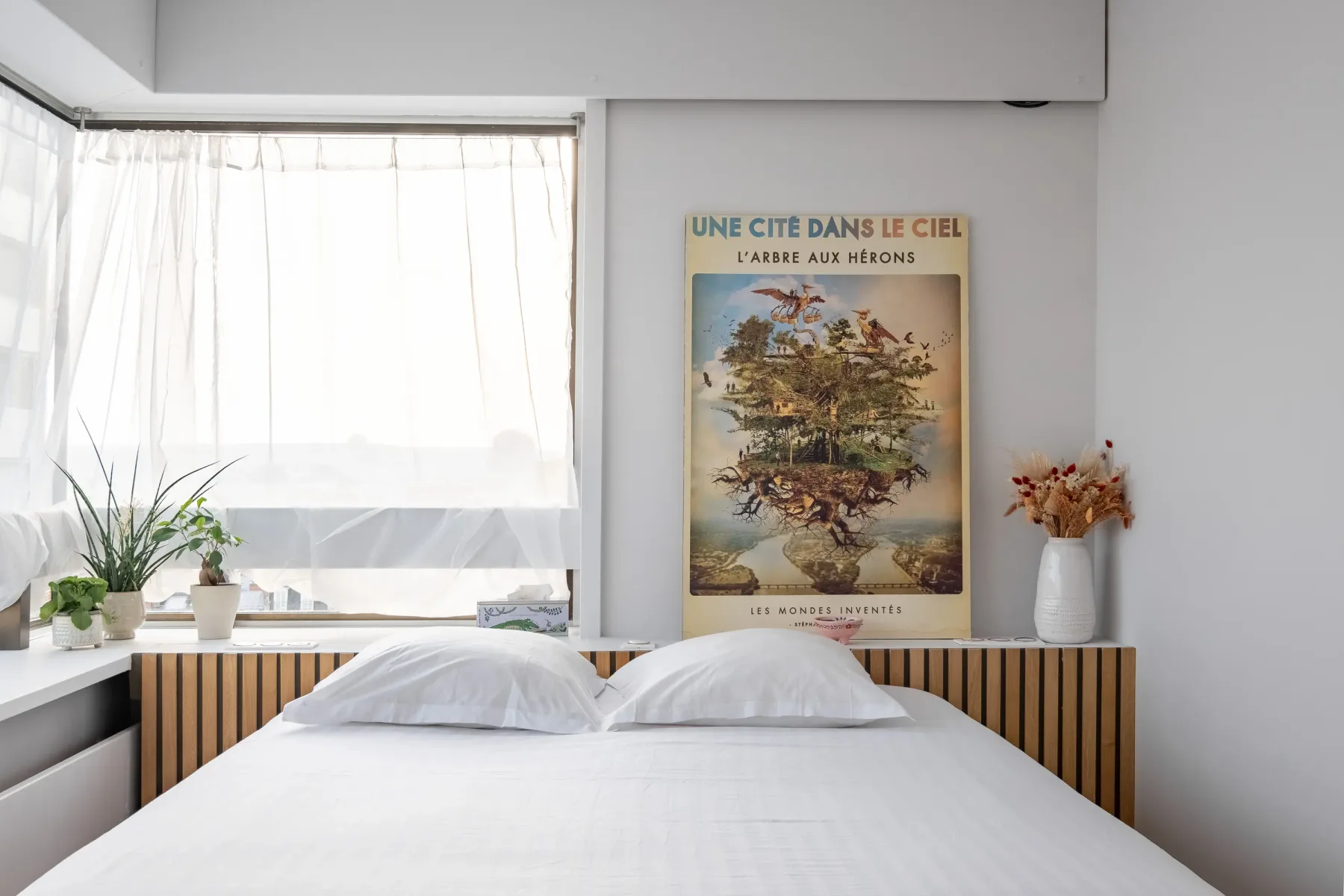 A bedroom with a neatly made bed beneath a framed wall print.