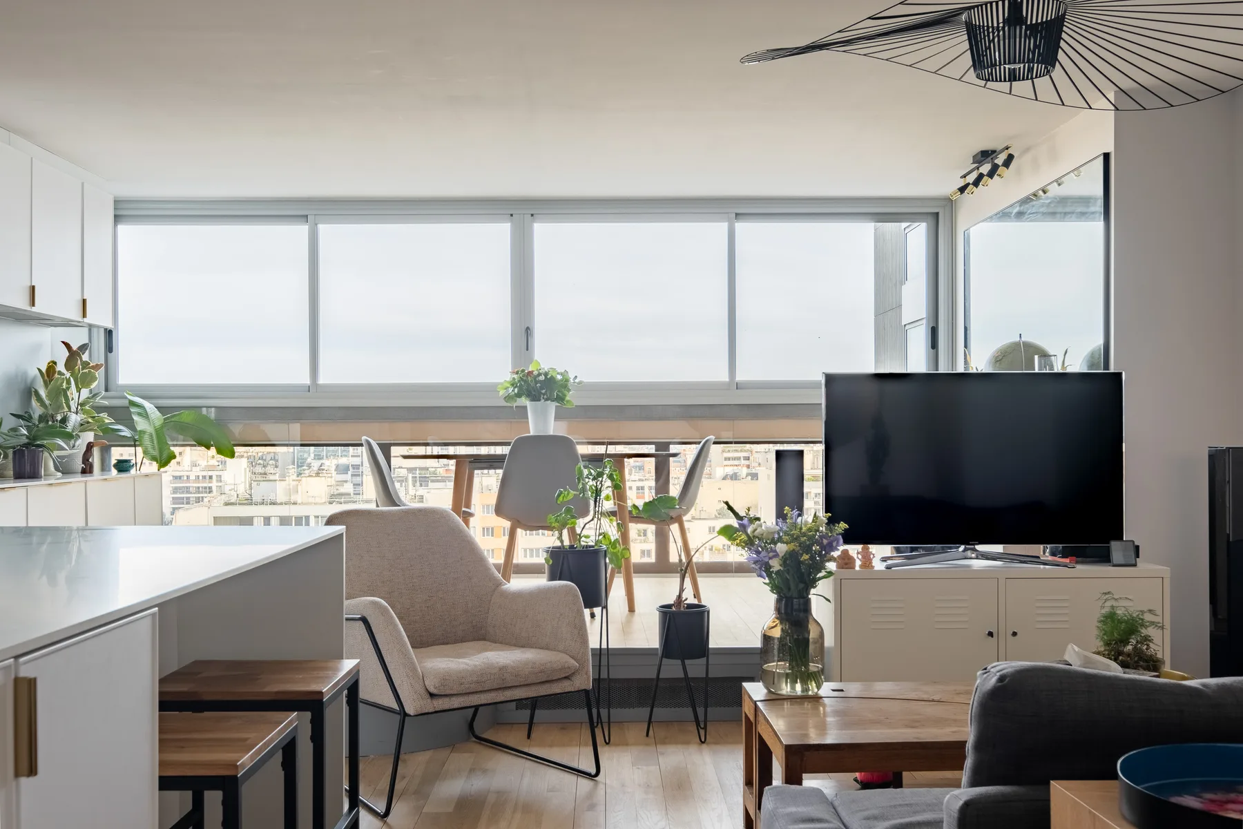 A bright living room with seating, a television, and wide windows.
