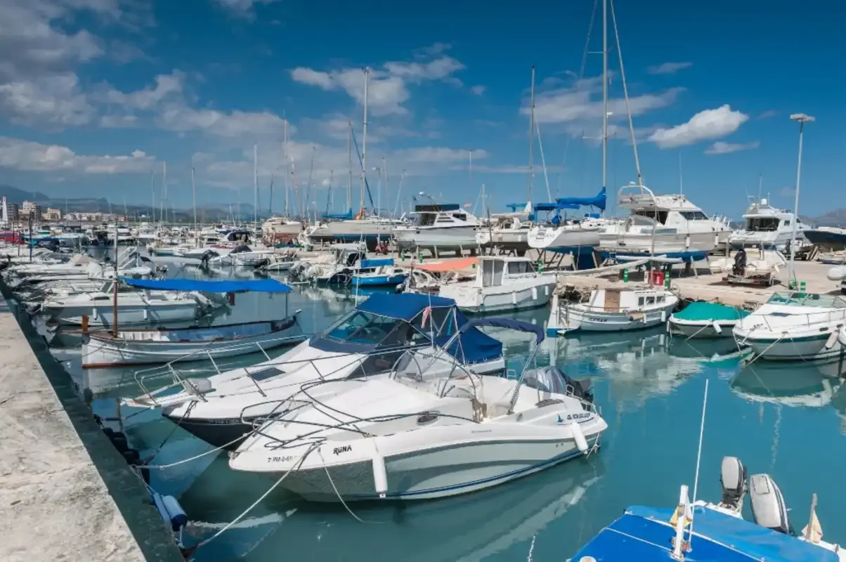 Boats are moored in a marina beside a waterfront walkway.