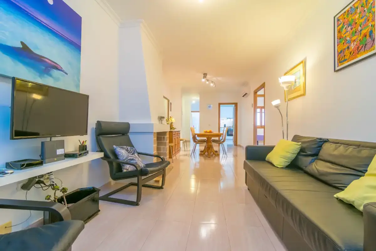 A living room with seating, a television, and a dining table in the background.