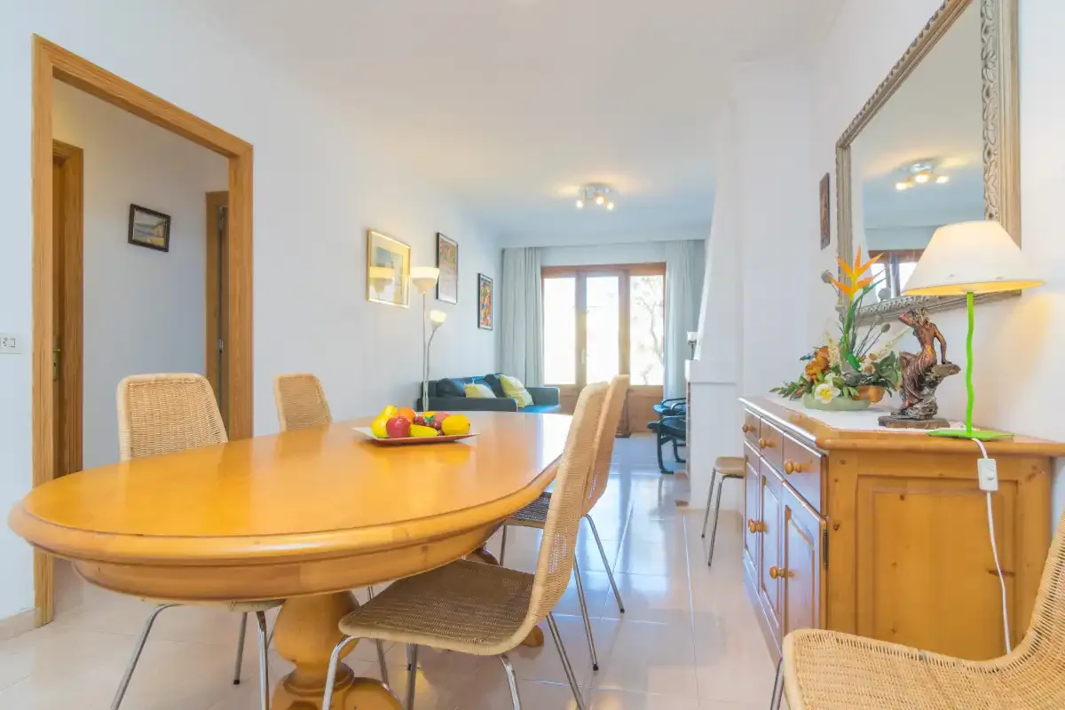 A bright dining area with a wooden table and seating opens toward a living room.