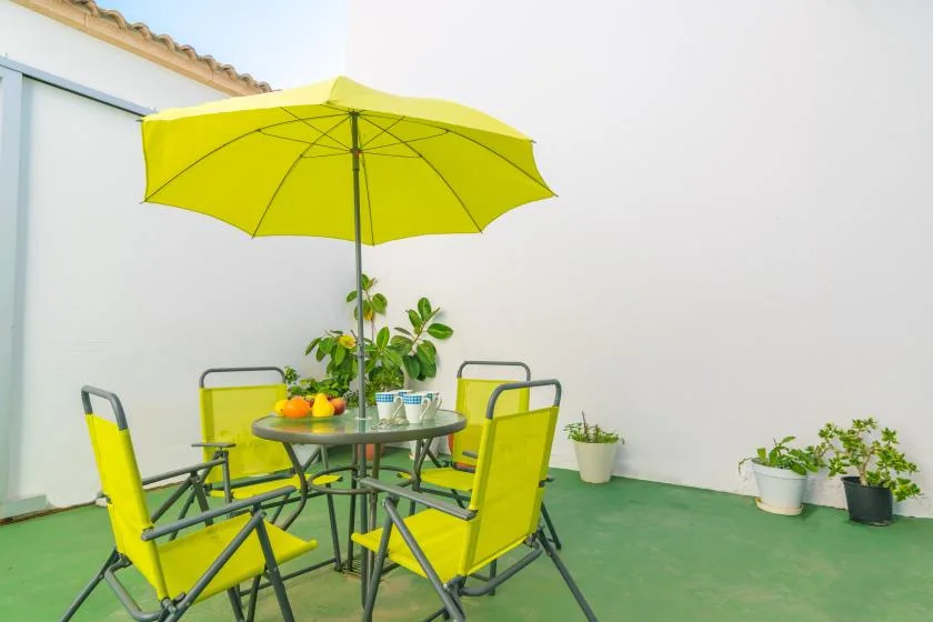 A patio seating area with bright yellow chairs beneath a large umbrella.