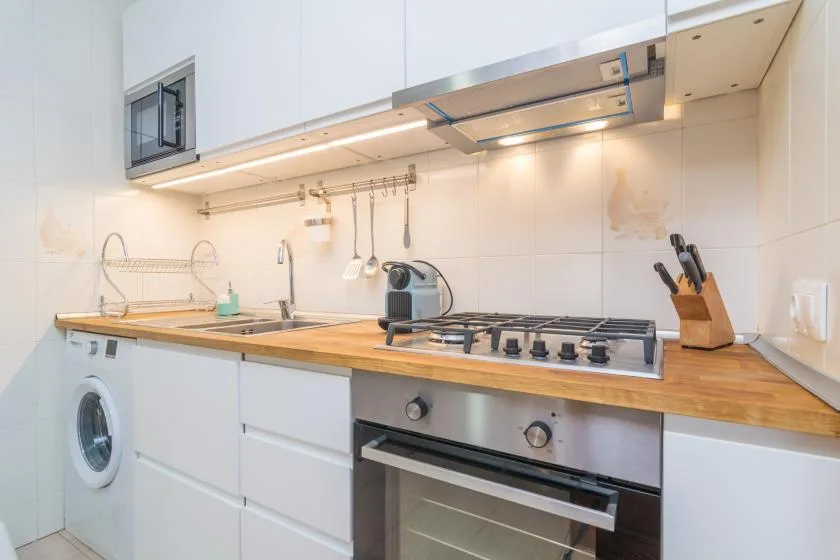 A modern kitchen with a cooktop, oven, and washing machine.
