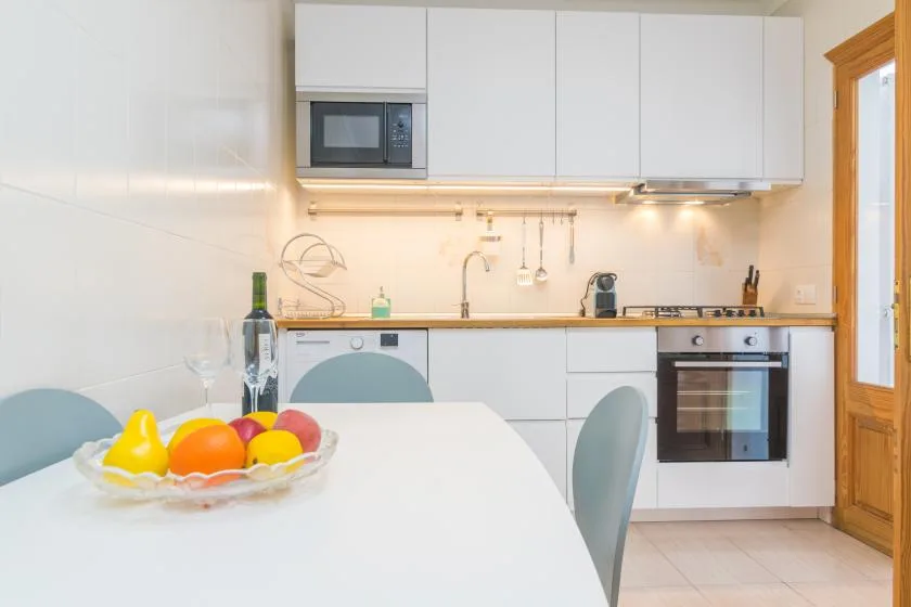 A bright kitchen with white cabinets, a countertop, and a dining table.