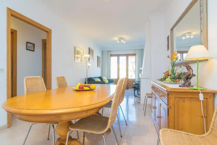 A dining area with a wooden table and seating opens onto a bright living room.