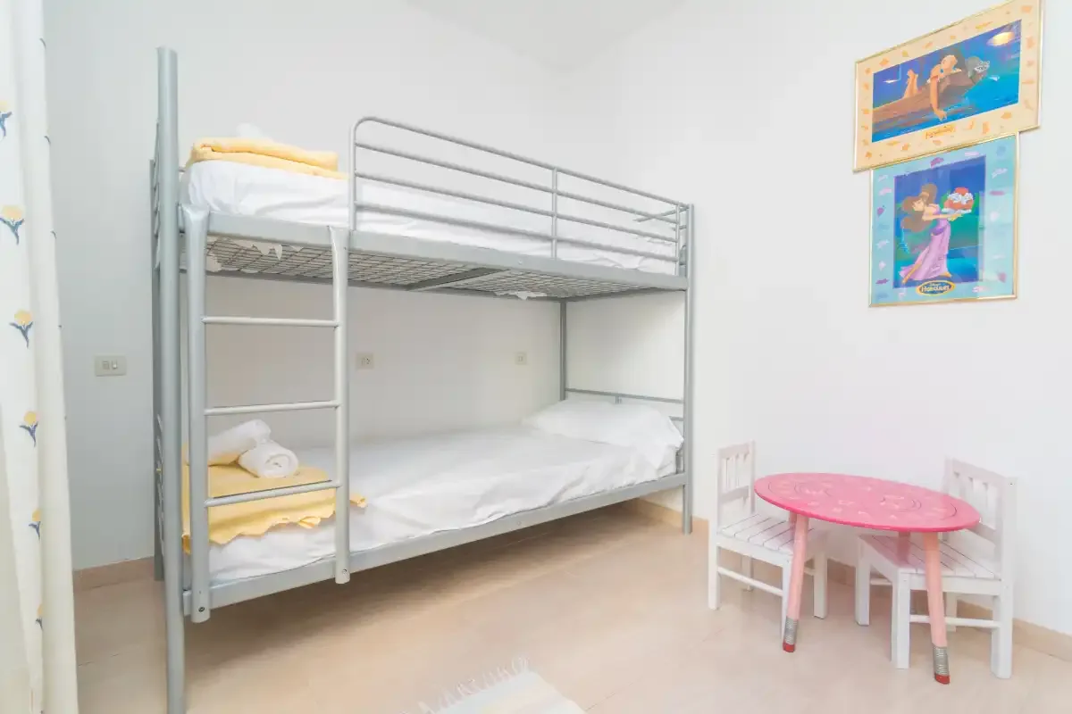 A bunk-bed sleeping area with a small pink table and chairs.