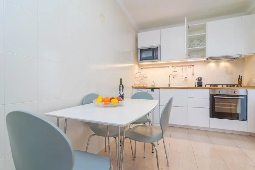 A bright kitchen with a dining table and white cabinetry.