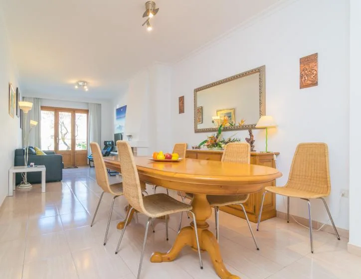 A dining area with a wooden table and seating, beside a bright living space.