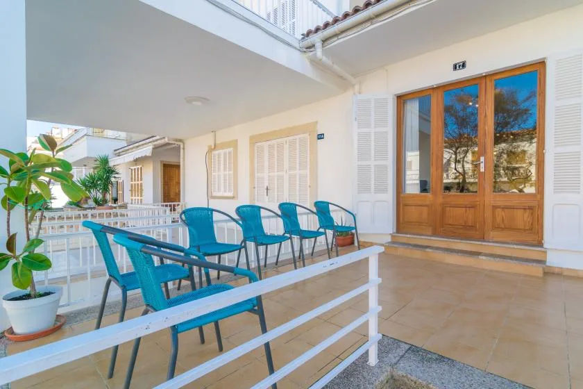 A covered terrace with turquoise seating and wooden doors.