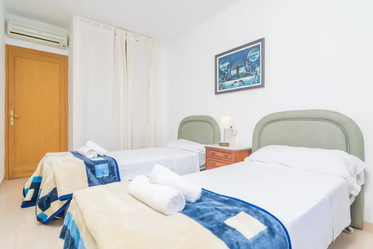 A bedroom with two beds and folded towels on the bedding.
