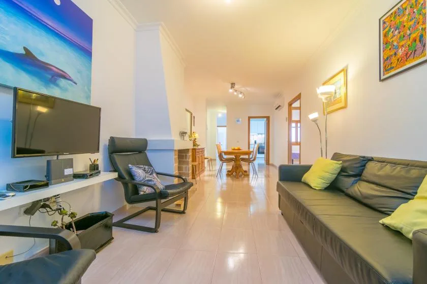 A living room with seating, a television, and a dining area beyond.