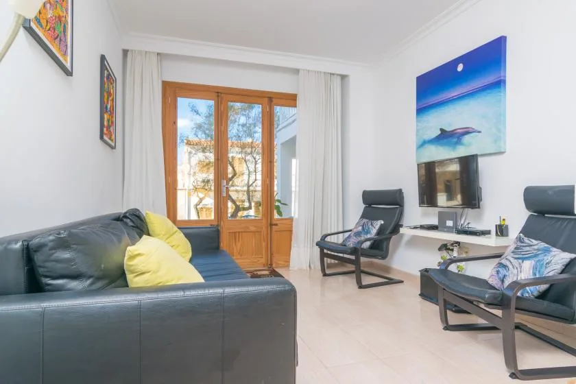 A living room with seating, a television, and wooden glass doors.