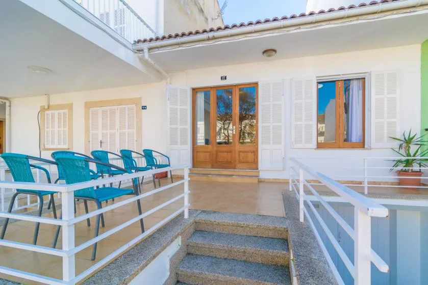 A courtyard patio with blue seating, shuttered windows, and a central entrance.