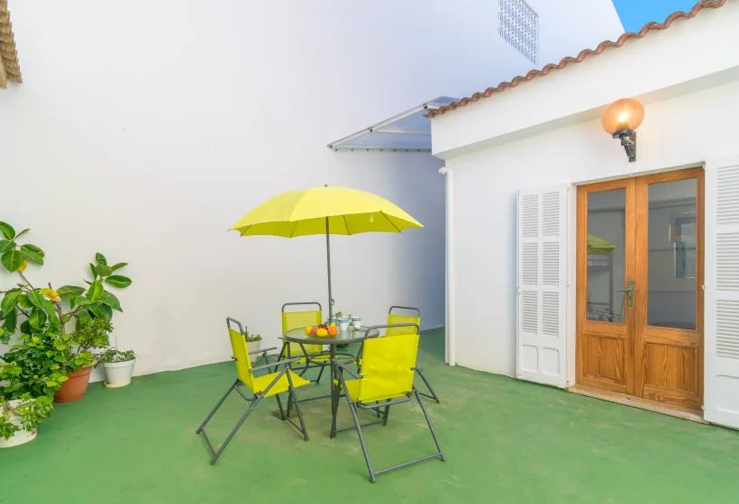 A small outdoor patio has a table and chairs beneath a bright yellow umbrella.