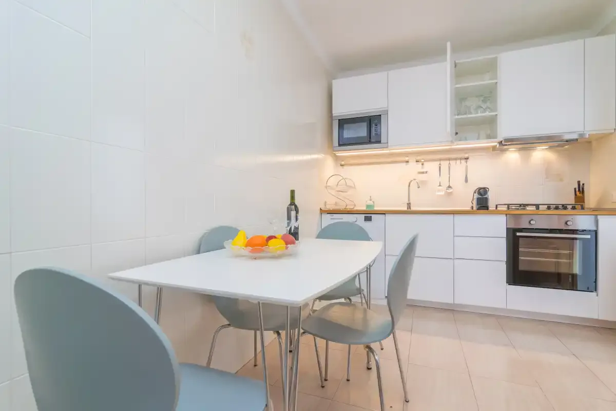 A bright kitchen with a dining table and white cabinets.