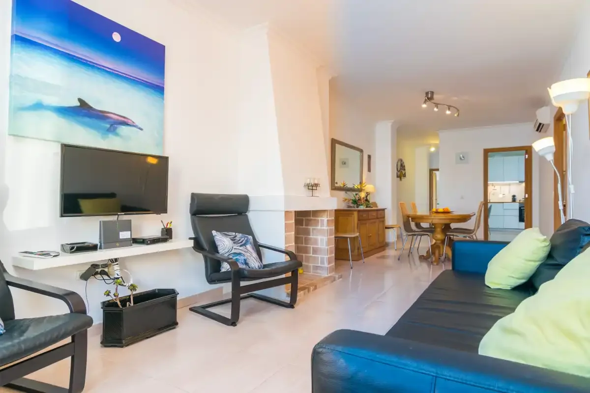 A living room with seating, a television, and a dining area.