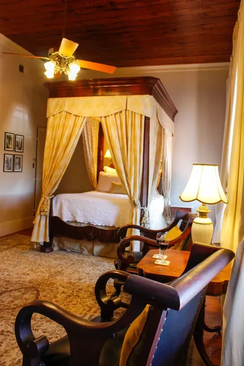 Guest room with a canopy bed and ceiling fan