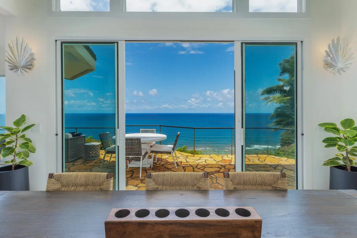A dining area opens onto a patio overlooking the ocean.