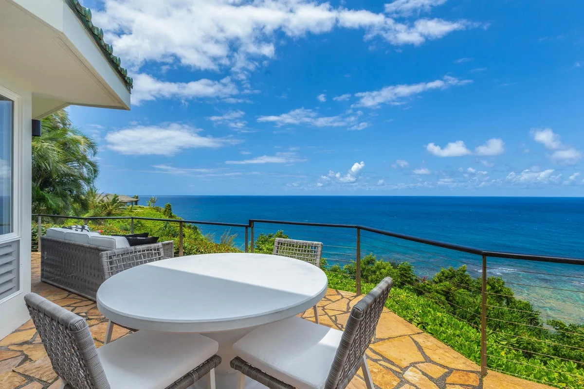 Un patio con vistas al mar, asientos al aire libre y una barandilla de vidrio.