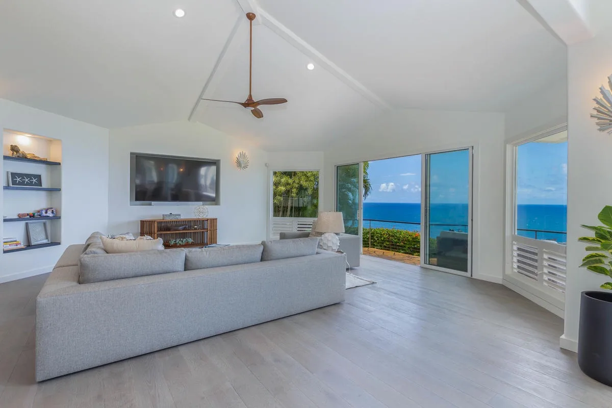 A bright living room with seating and large windows overlooking the ocean.