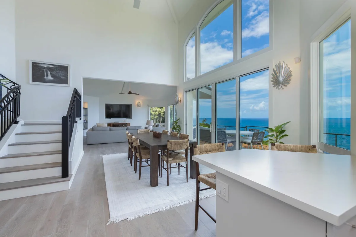 A bright open-plan living and dining area has large windows overlooking the ocean.