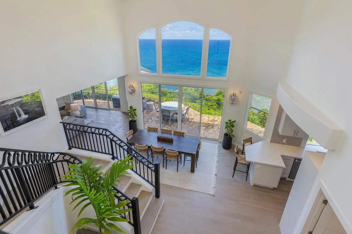 A bright open-plan living and dining area overlooks the ocean through large windows.