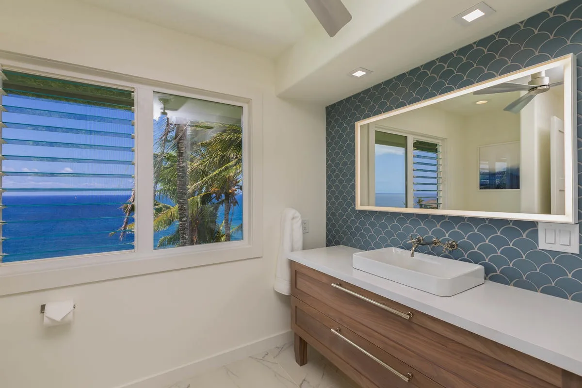 A bathroom vanity with a wide mirror and windows overlooking the ocean.