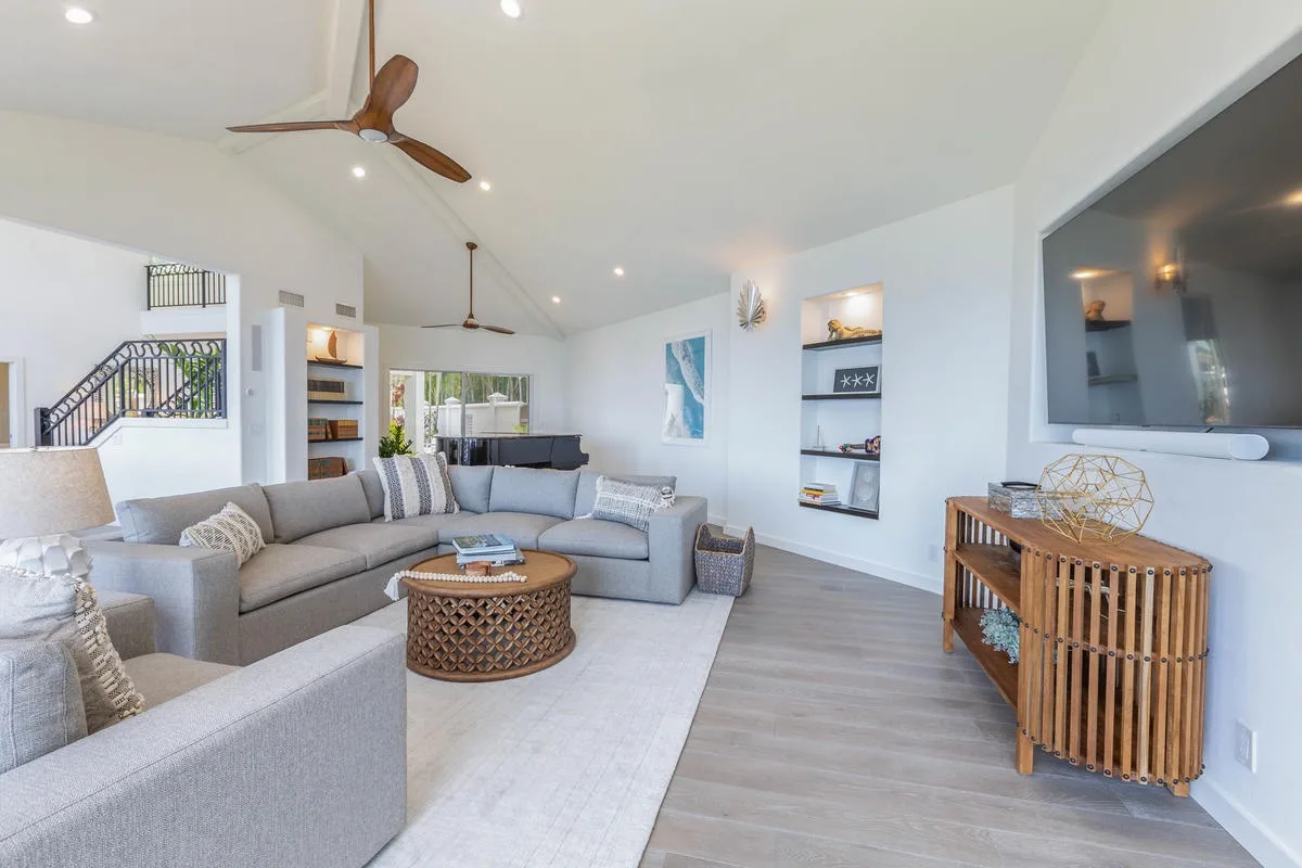 A bright living room with sectional seating, a coffee table, and a wall-mounted television.