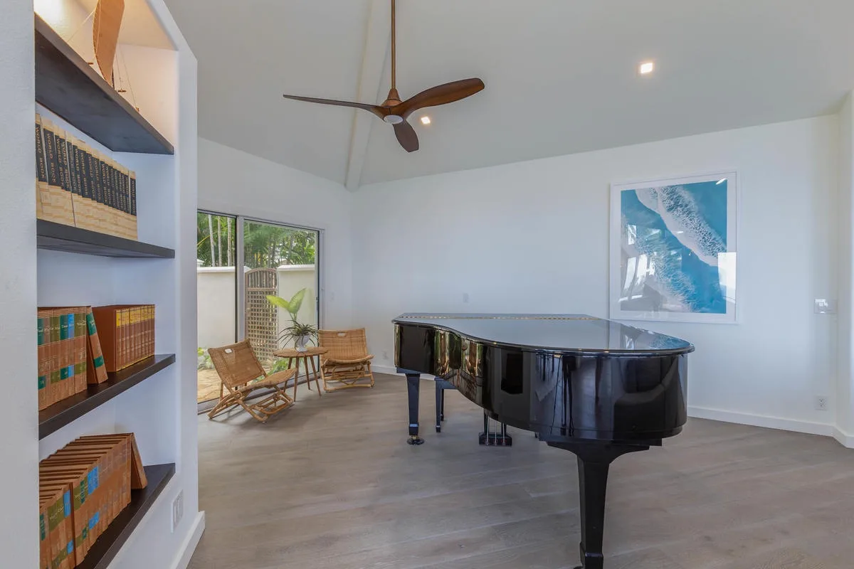 A bright living room features a black grand piano beside built-in bookshelves.
