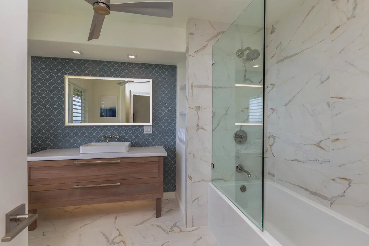 A bathroom with a wood vanity, wall mirror, and glass shower enclosure.