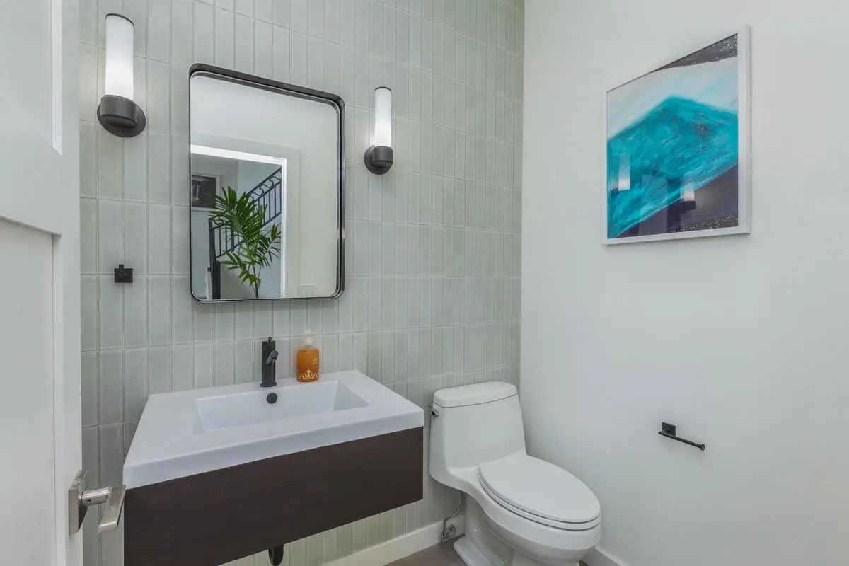 A bathroom with a wall-mounted sink, mirror, and toilet.