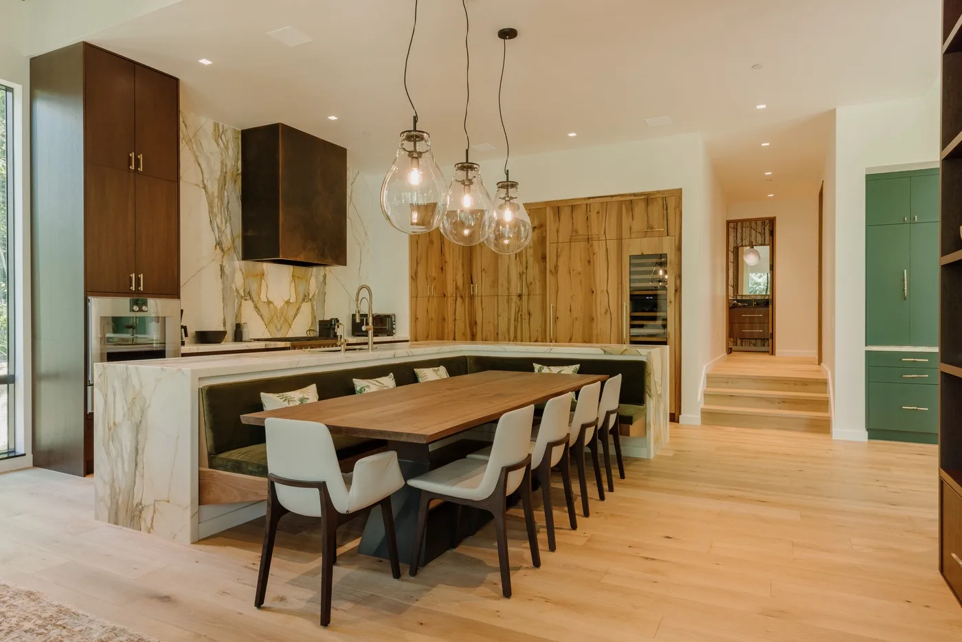 Comedor con una larga mesa de madera junto a una cocina abierta.