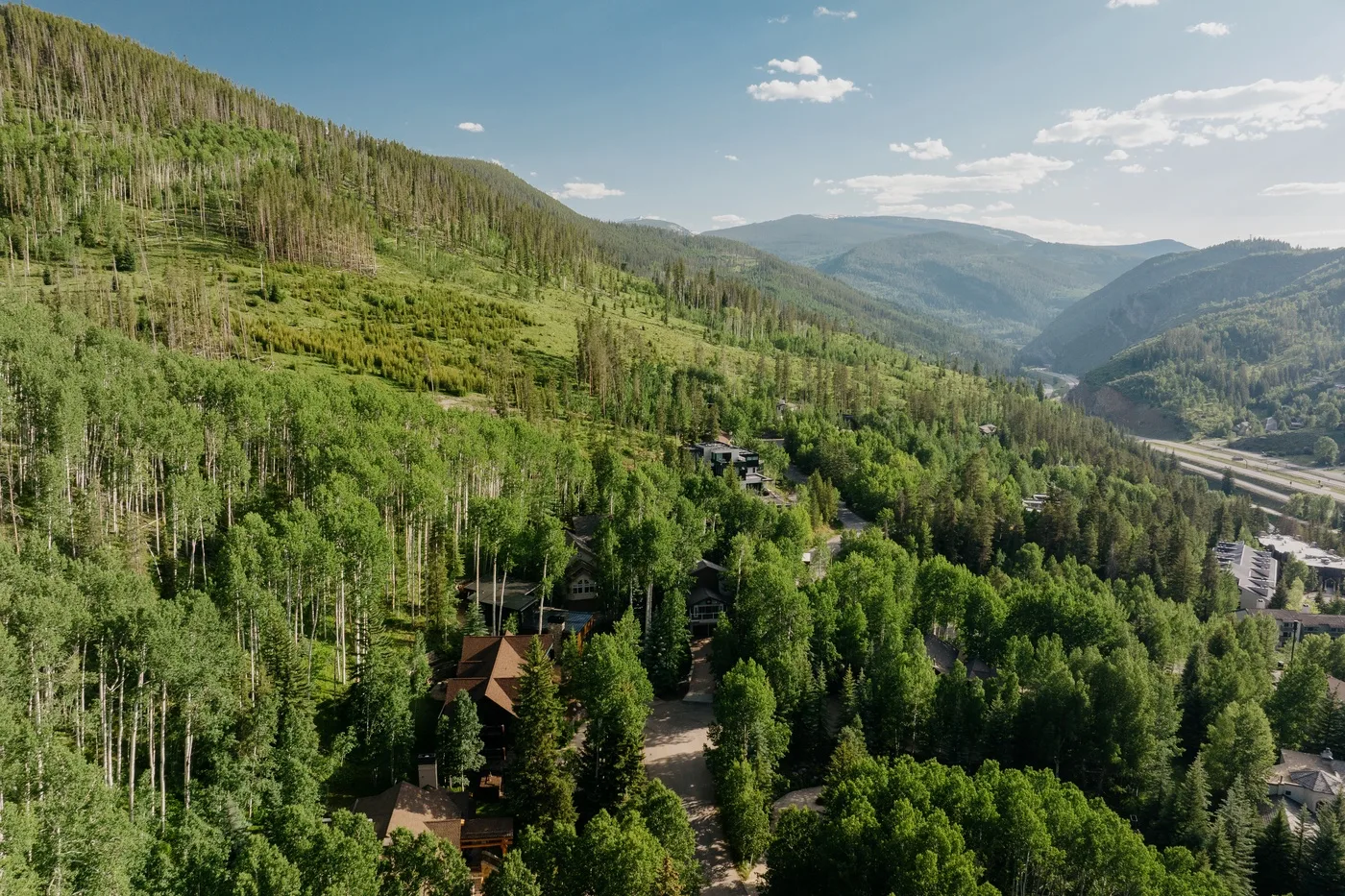 Vista aérea de un valle montañoso boscoso con edificios dispersos.
