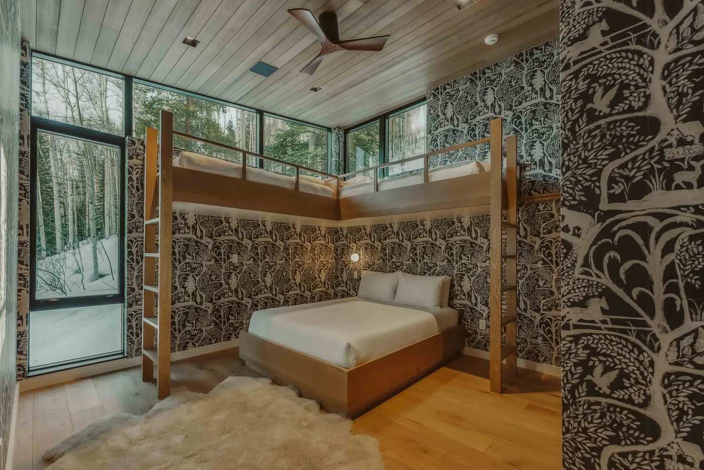 Un dormitorio con una cama debajo de un altillo de madera y grandes ventanas.
