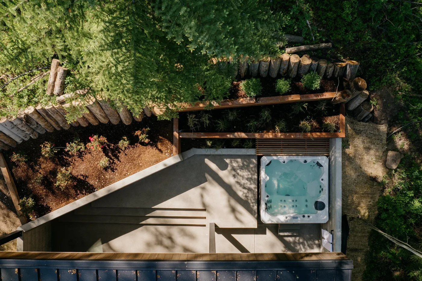 Un patio al aire libre con una bañera de hidromasaje rodeada de vegetación.