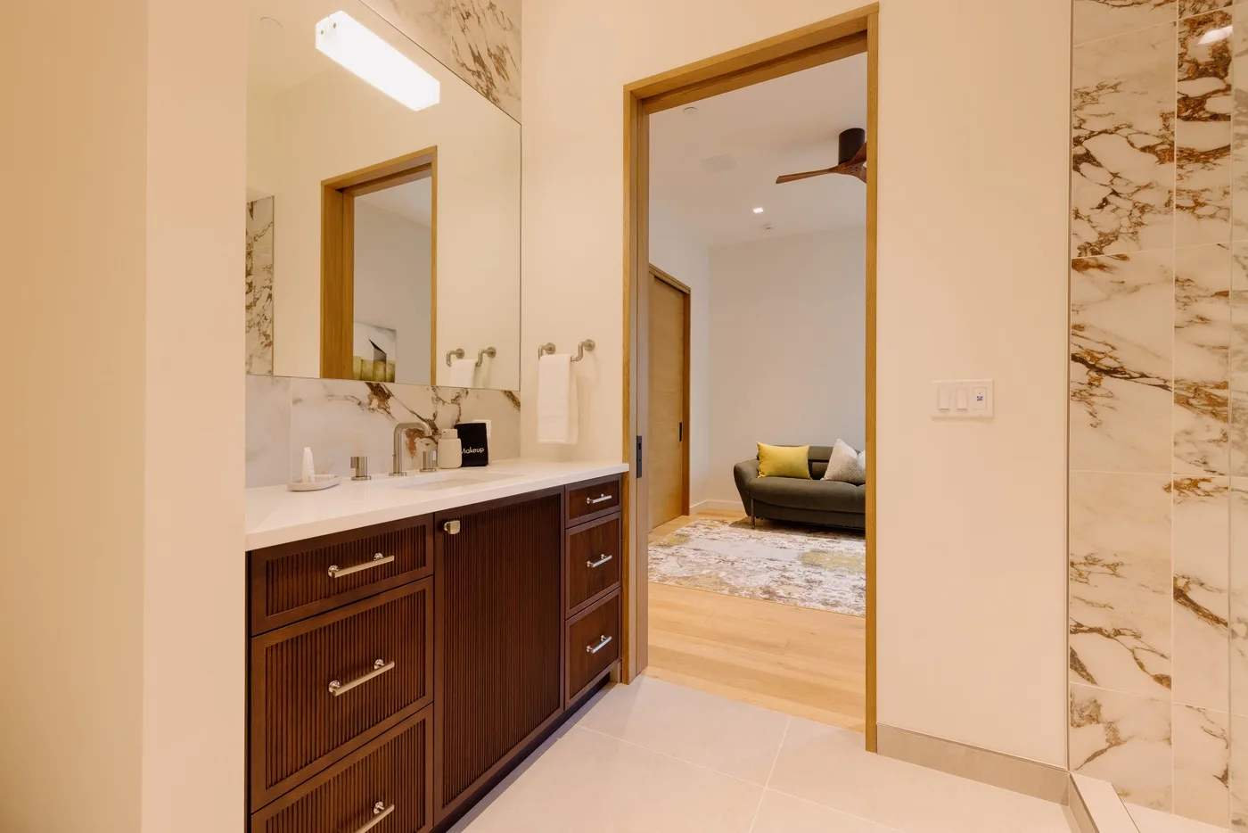 Un lavabo de baño da paso a una zona de estar con un sofá.