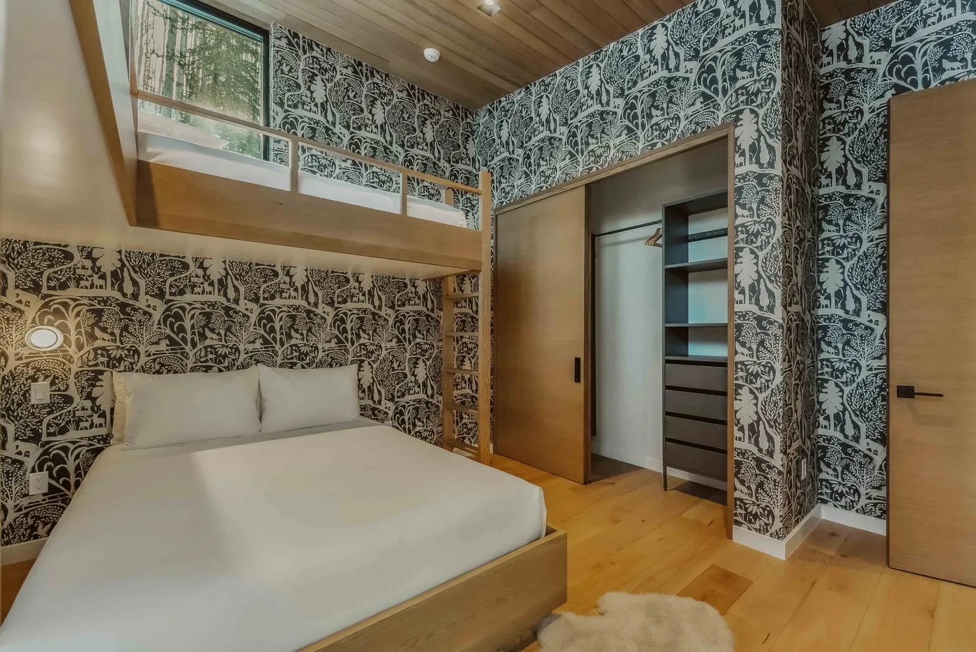 Un dormitorio con una cama bajo un altillo de madera y paredes estampadas.