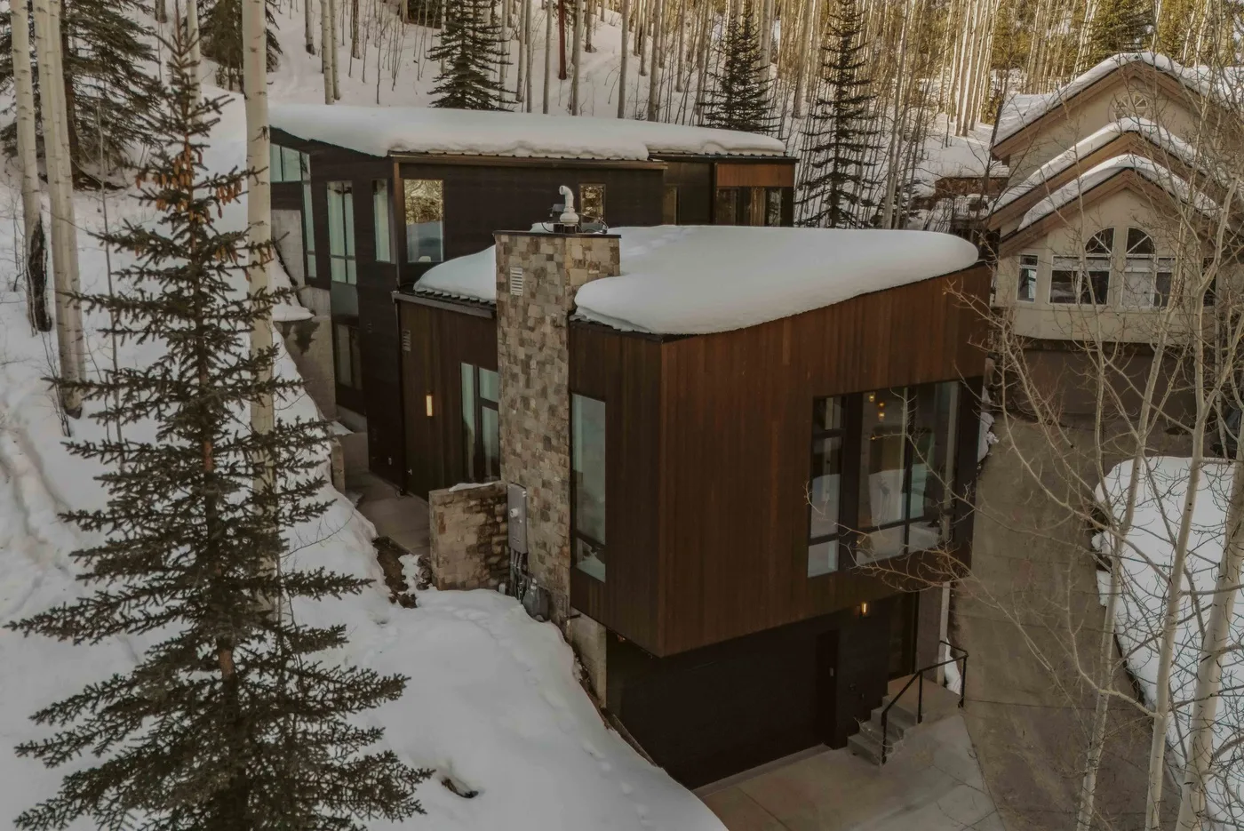Una casa moderna se encuentra entre árboles cubiertos de nieve en un paisaje invernal.