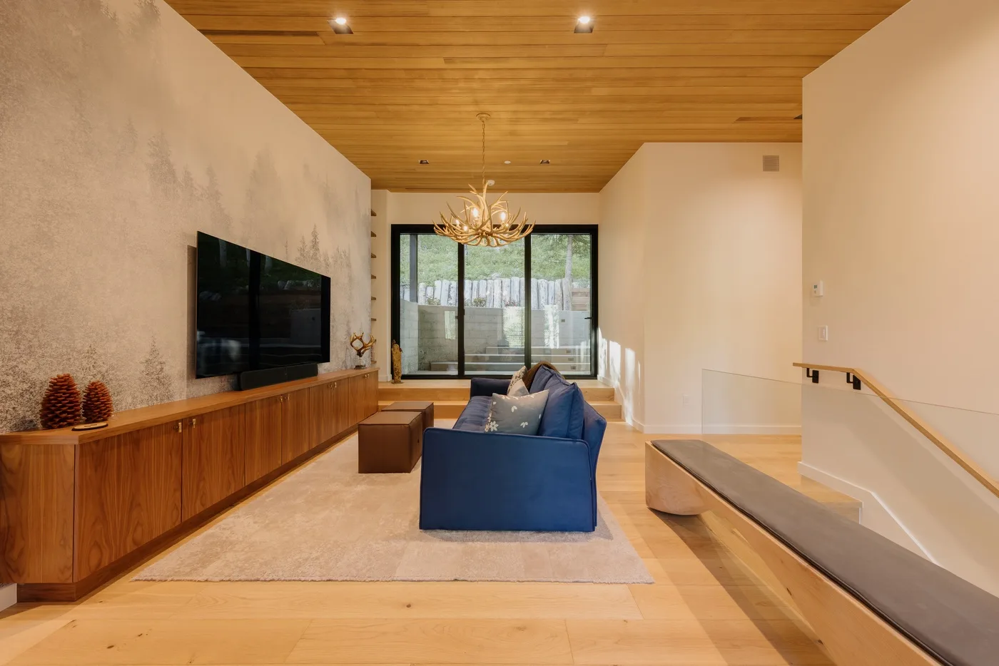 Una sala de estar moderna con asientos azules, un televisor y puertas corredizas de vidrio.