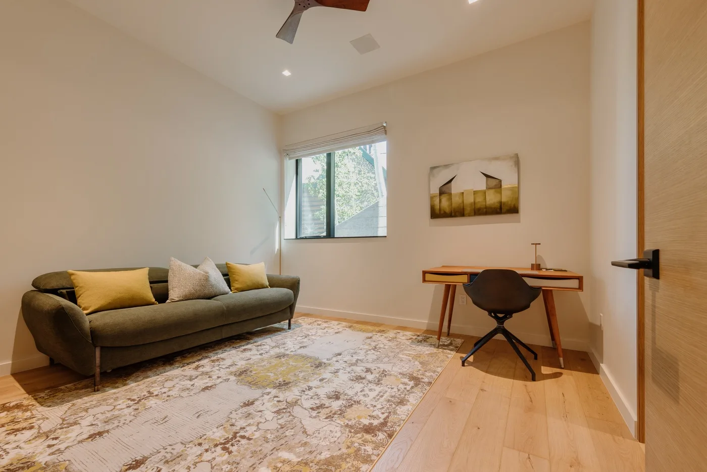 Una habitación luminosa con sofá, escritorio y ventana.