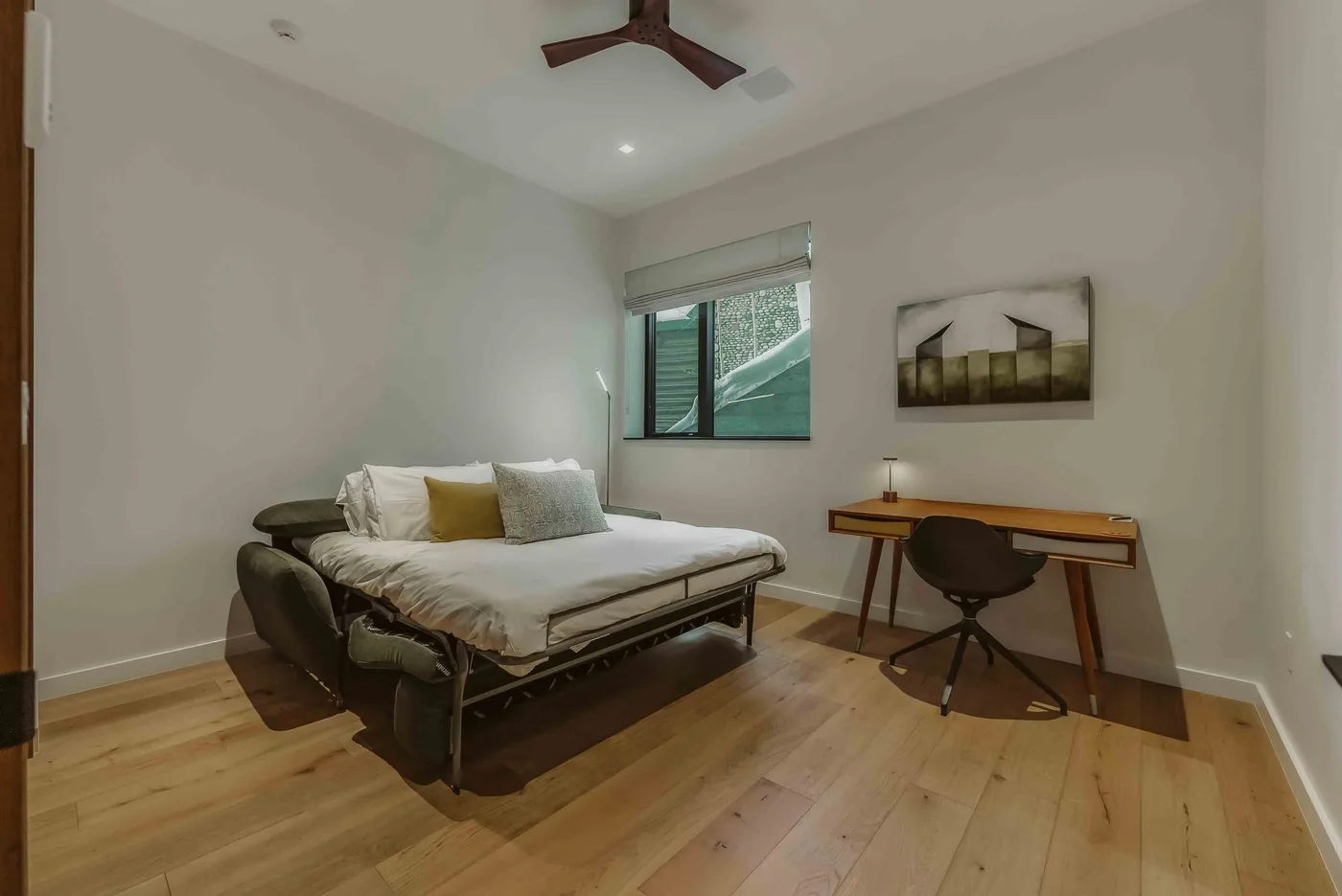 Dormitorio con una cama, un escritorio y una ventana.