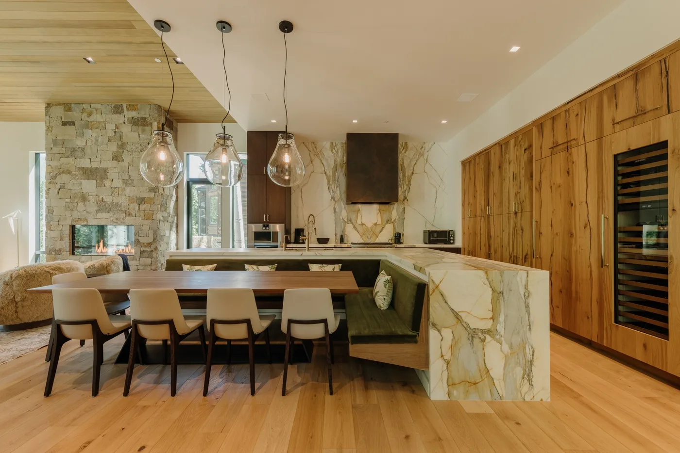 Una cocina y comedor modernos con una mesa larga y lámparas colgantes.