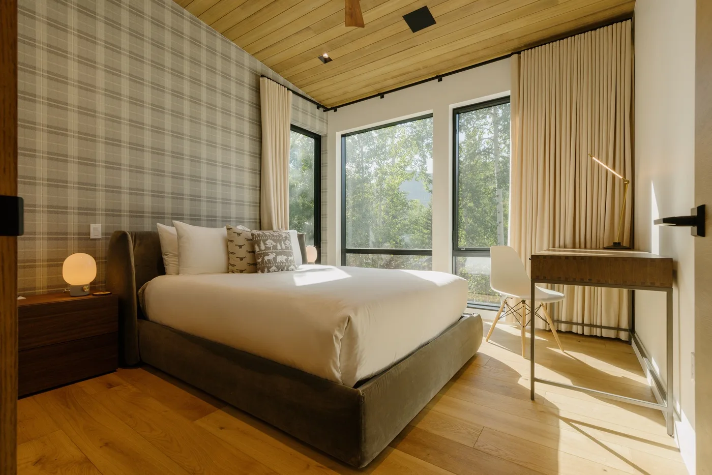 Un dormitorio con una cama, grandes ventanas y un escritorio.